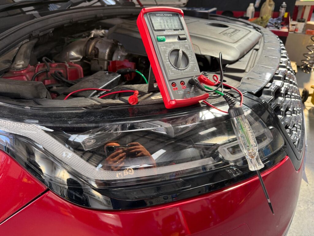 Diagnosticarea sistemului electric al unui far modern cu LED, folosind un multimetru în service-ul auto Carfix din Londra.
