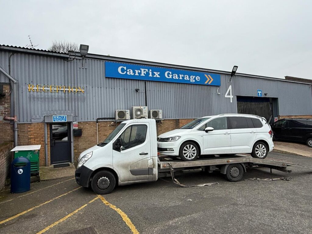 O mașină albă cu partea frontală avariată, tractată pe o platformă auto pe o stradă din Londra.