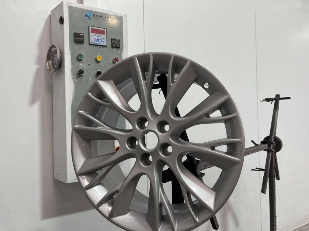 Refurbished alloy wheel mounted in a spray booth after welding and straightening at a Romanian car welding workshop in London